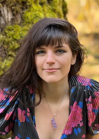 Agustina Forest smiling with nature in the background.