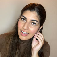 An woman with long straight brown hair touches her face lightly