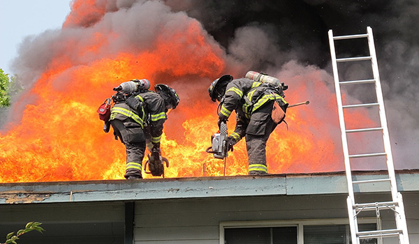 Two firefighters on top of a roof on fire