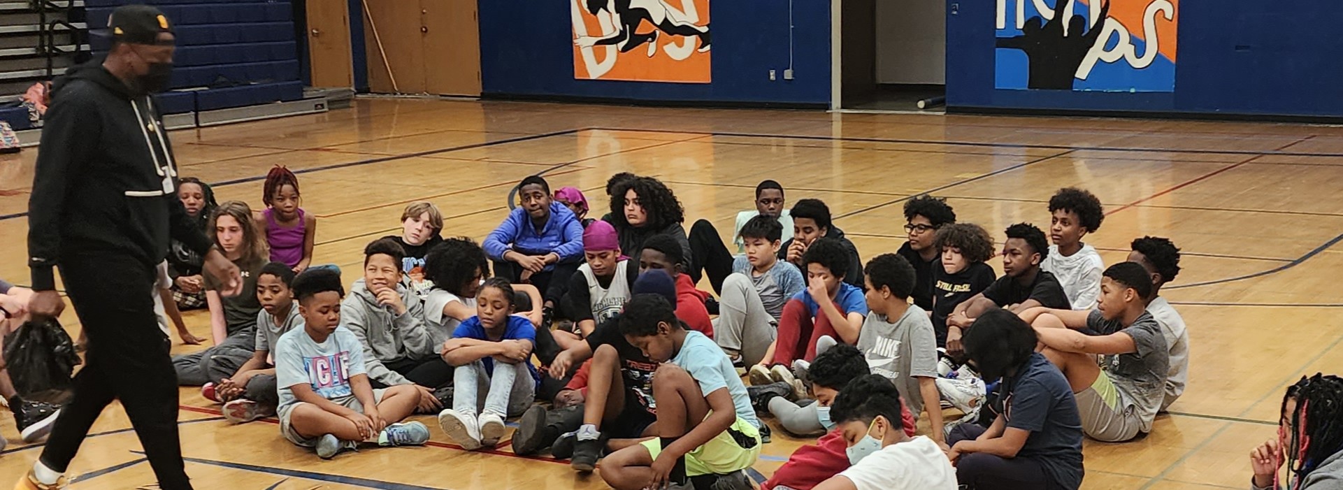 Community Learning Centers youth receive game play instructions on an indoor basketball court.