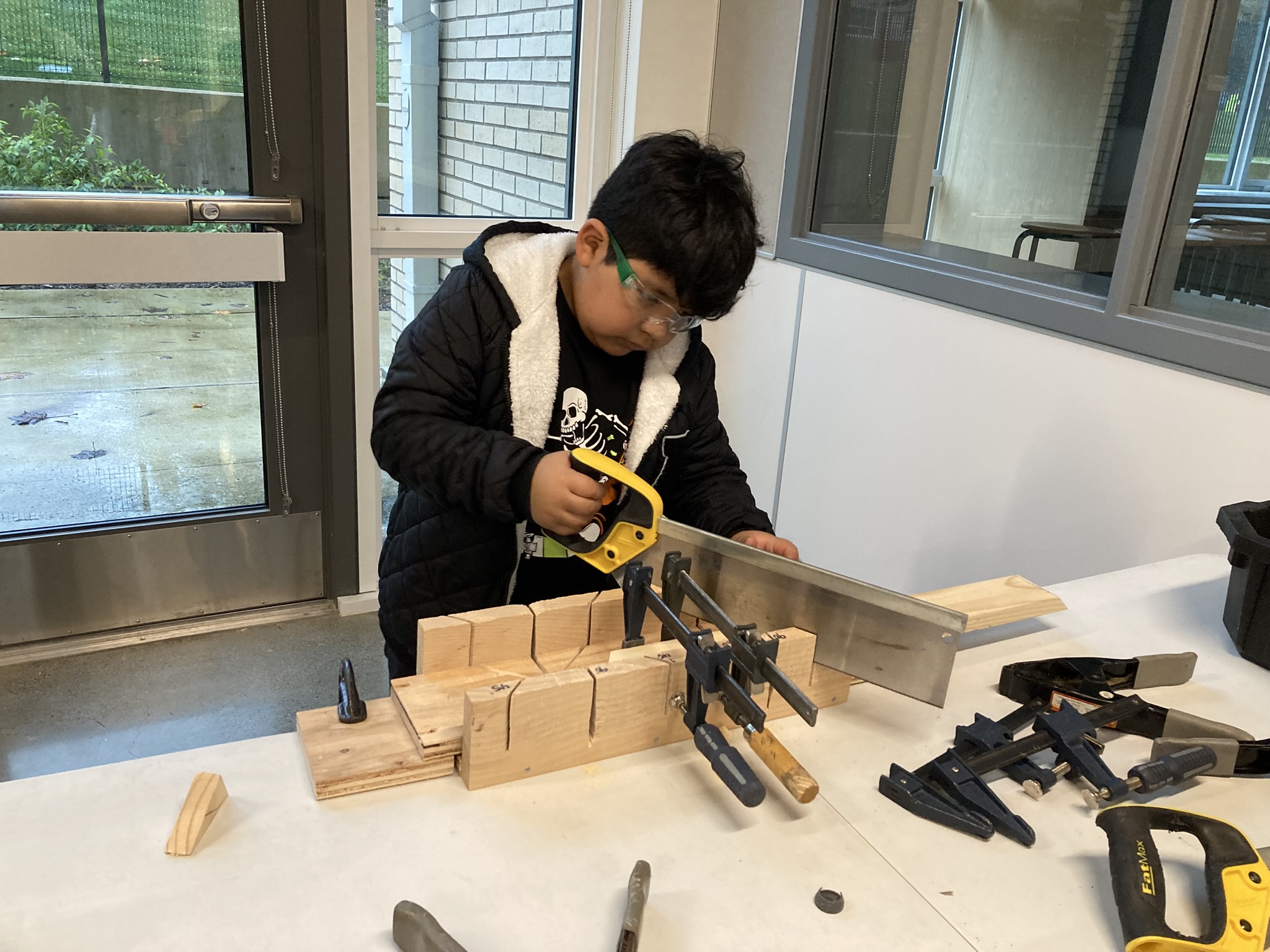 A Community Learning Center participant practices sawing wood