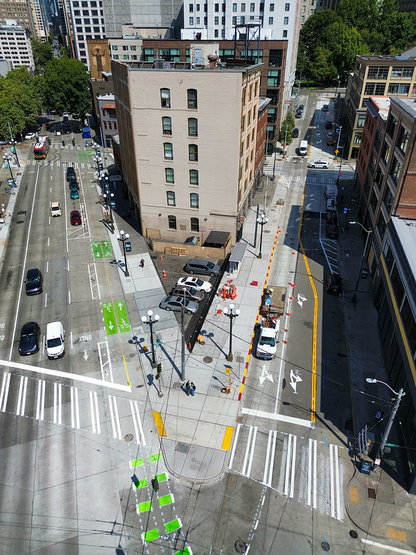 An overhead shot of 3rd and Main nearly completed, with our crews still working to construct the sidewalk. Orange safety cones are all over the area where the bus shelter will go