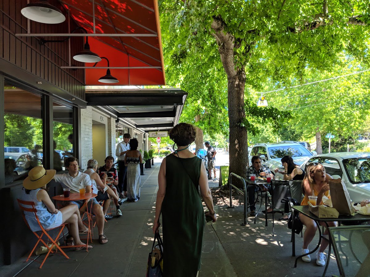 Awning over sidewalk cafes and person walking down the street