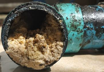 A drain pipe clogged with thick sludge.