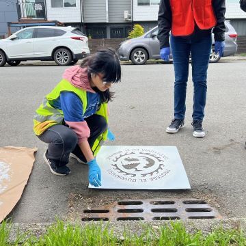 Volunteer places a stencil sheet next to a grate.