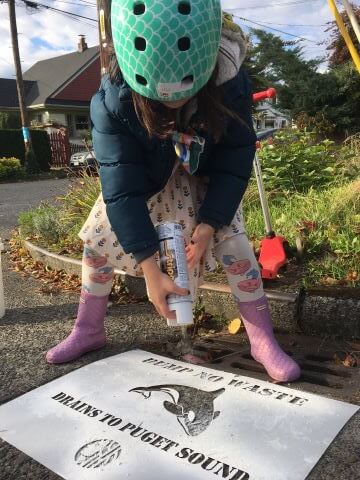A child spray paints a stencil.