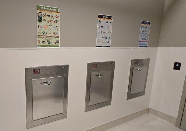 A wall with three chute hatches and informational posters.