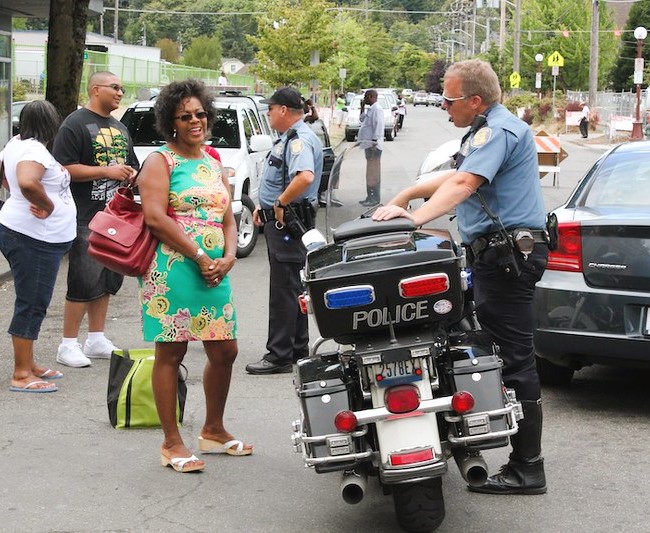 Community members attending the Rainier Valley Heritage Parade chat with uniformed Seattle police officers on the parade route