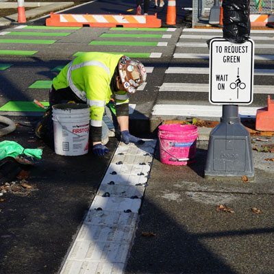 A crew member putting in a tactile strip during construction of the waterfront