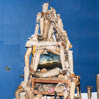 Artificial legs arranged in a pyramid formation. A suitcase of a helicopter on fire in the middle.