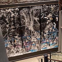 View of three panels of artwork of trees displayed in the stairwell of ARTS at King Street Station