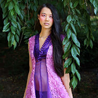 Model Vivian Lake wearing a dress with two panels of pink rose chiffon rosettes with a panel of purple mesh in the center.