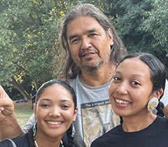 Two Head Young Women Dancers smile with a tall artist behind them.