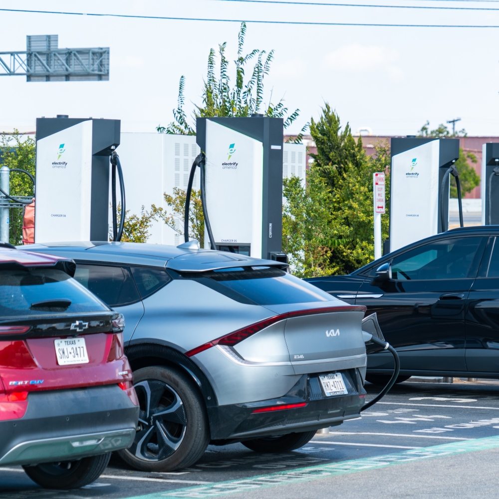 Multiple Electric Vehicle fast charging stations all in a row with car parked at them charging.