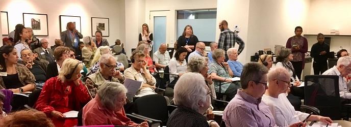 An audience of older adults waits for an event to begin.