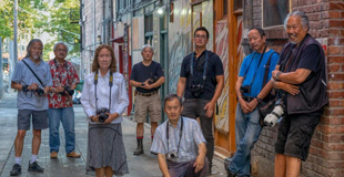 Group of people standing in an alley in Chinatown with their cameras around their necks.