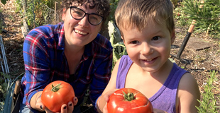 Two P-Patchers smiling and showing off their huge, shiny, red tomatoes.