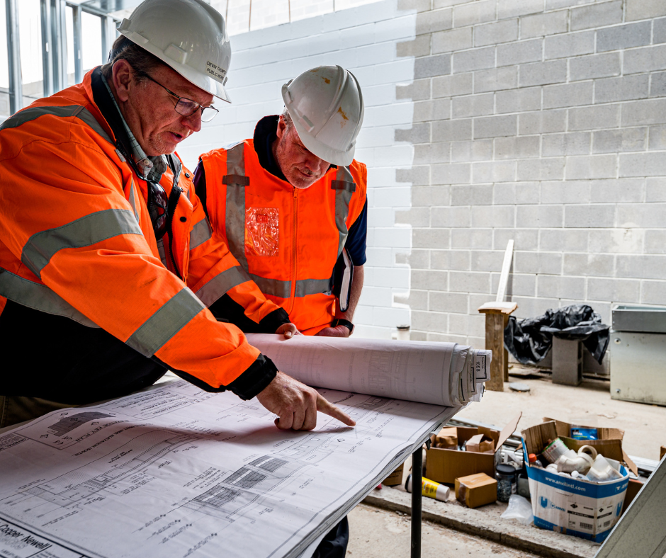 Construction workers reviewing blueprints on a desk