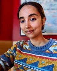 Close up of Akiksha Chatterji from the shoulders up smiling in colorful attire.  