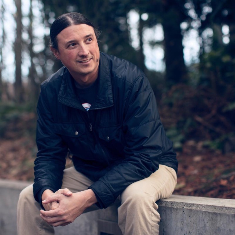 Photo of Matt Remle sitting outside looking away from the camera in semi-professional attire.  