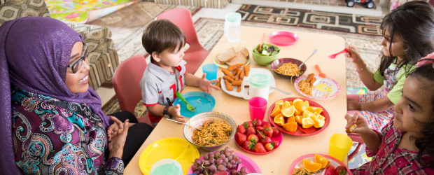 A teacher and students eating lunch at a table filled with fruits and vegetables