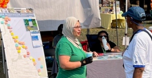 A Community Engagement Ambassador speaks at an outdoor event