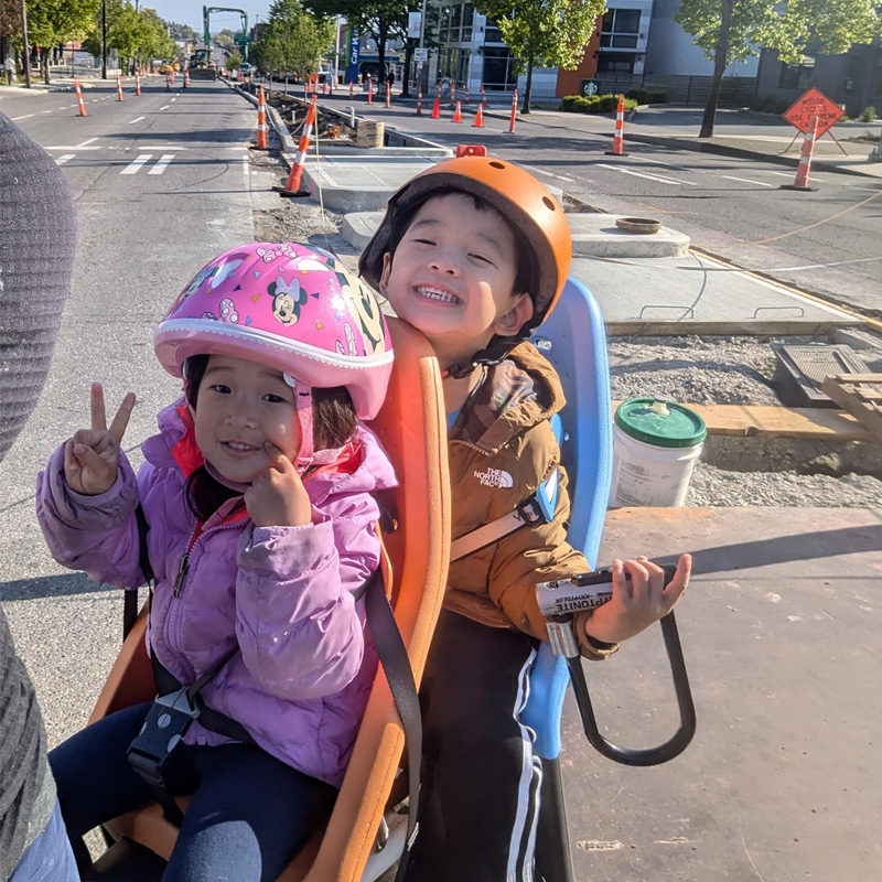 Children on the back of the bike smiling with peace signs