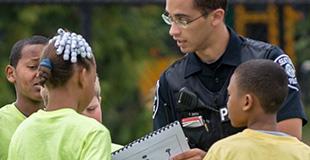 A police officer hands out materials to youths in a park